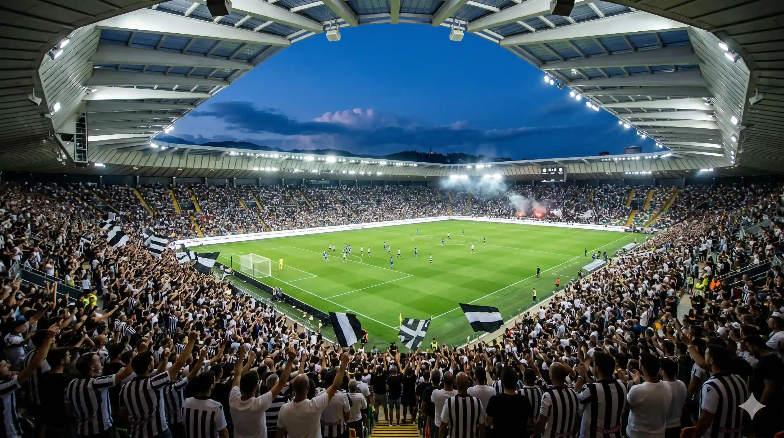 Udinese fans in black and white at dynamic Bluenergy stadium night.